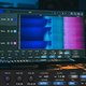 A close-up shot of the Spectrum 2 plugin UI, showing a multi-channel spectrogram with different colored lines representing distinct audio tracks. The UI is clean and modern, integrated into a dark, professional DAW environment on a studio monitor. Soft, f