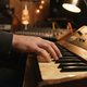 A close-up shot of a hand gently pressing keys on a vintage synthesizer, with soft, warm studio lighting. The focus is on the fingers and keys, conveying the act of musical creation and melodic thought. The background is slightly blurred, hinting at a coz