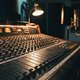 A moody, close-up shot of a professional mixing console with faders and knobs, soft focus on a microphone in the background, conveying a focused studio environment. No screens or UIs visible.
